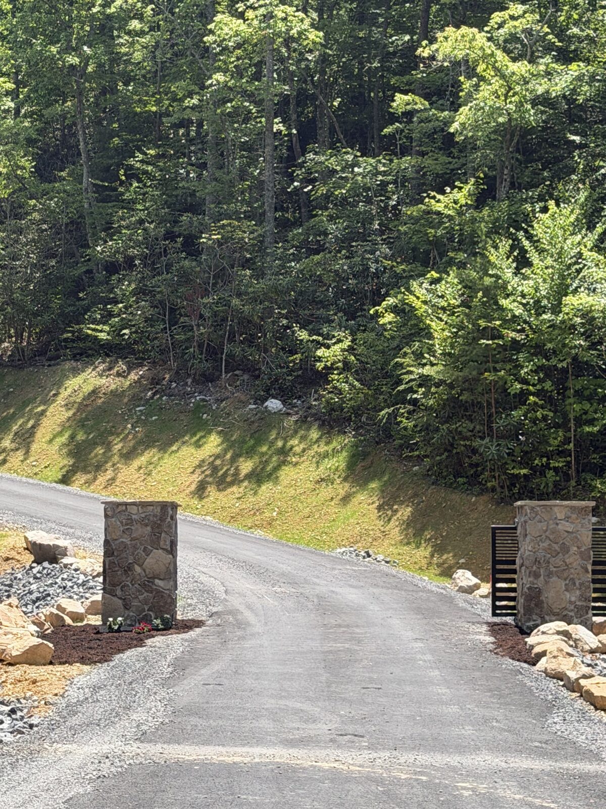 Twin stone entrance columns with black horizontal gate panels at the entrance road of the Smoky Mountain Overlook community