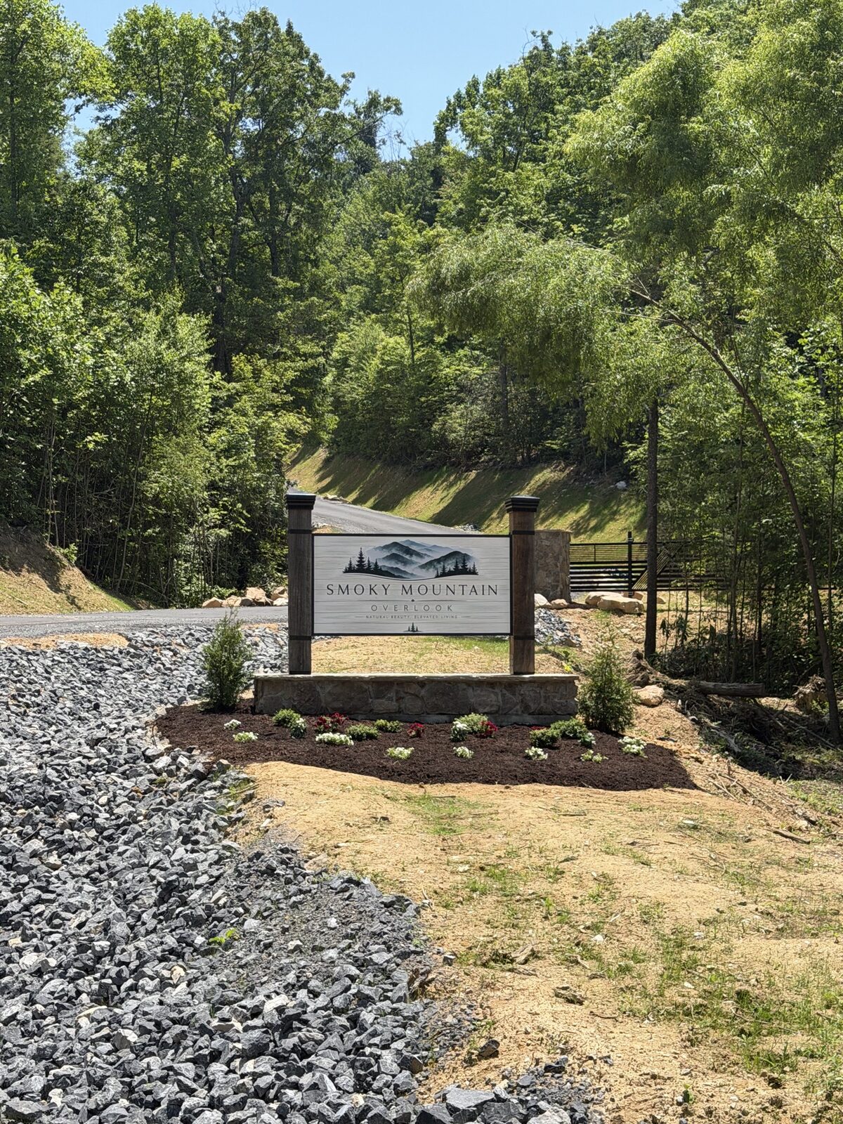 Stone entrance monument reading Smoky Mountain Overlook — Natural Beauty. Elevated Living. — at the entry to a newly developed mountainside community